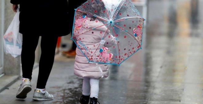 Una niña con un paraguas camina acompañada de su madre por una calle de Lugo hace unos días. EFE/ Eliseo Trigo