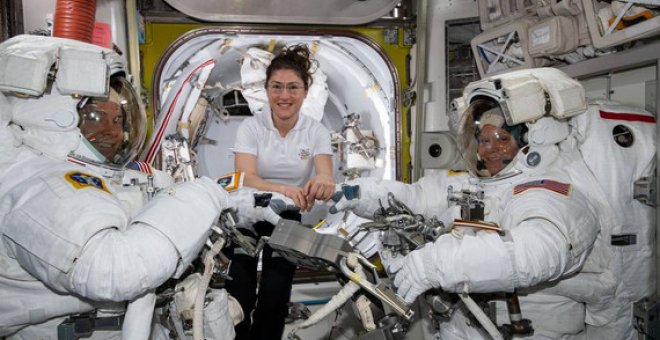 La astronauta de la NASA Christina Koch (centro) asiste a sus compañeros astronautas Nick Hague (izquierda) y Anne McClain (derechea) para ajustar sus trajes espaciales poco antes de comenzar su primer paseo espacial el pasado 22 de marzo. / NASA