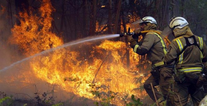 Los bomberos apagan uno de los numerosos focos del incendio en la localidad coruñesa de Rianxo. (LAVANDEIRA JR. | EFE)