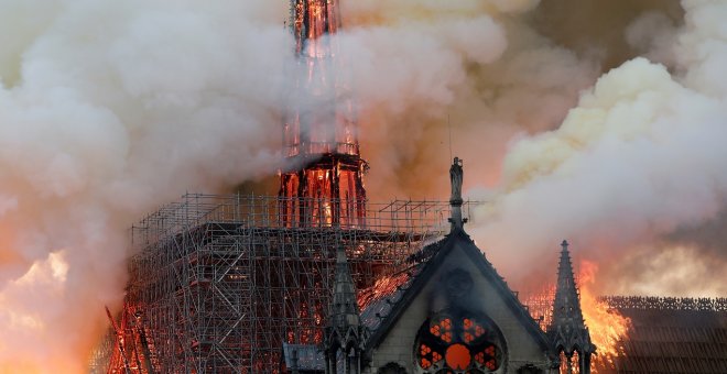 El humo ondea cerca de los andamios cuando el fuego envuelve la aguja de la catedral de Notre Dame. / Reuters