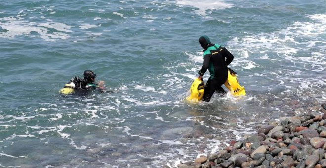 Dos submarinistas de la Guardia Civil se preparan para sumergirse y continuar con la búsqueda de los inmigrantes desaparecidos en el mar tras desembarcar de una patera en el sur de Gran Canaria. /EFE