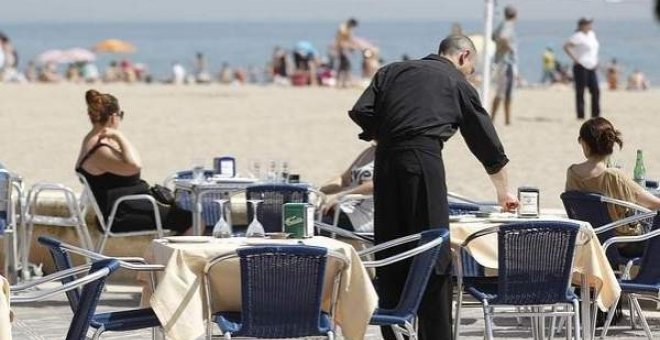 Un camarero atiende las mesas de un restaurante junto a la playa. EFE