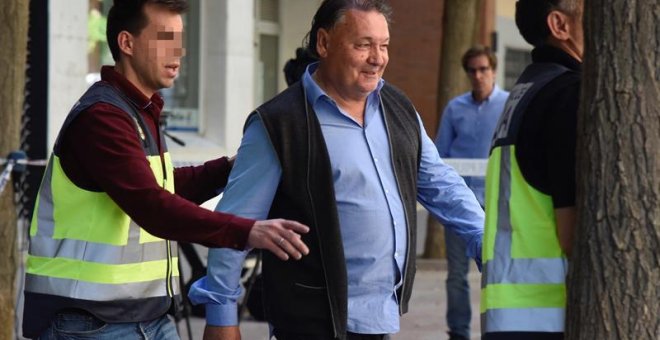 El presidente del Huesca, Agustín Lasaosa,d., junto a un policia a su salida de las oficinas del club tras ser detenido. /EFE