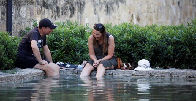 Unos turistas se refrescan en una de las fuentes de Córdoba. EFE/Salas