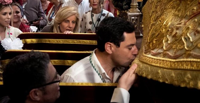 El presidente de la Junta de Andalucía, Juanma Moreno, besa el manto de la Virgen del Rocío en la aldea almonteña de El Rocío (Huelva). EFE/Julián Pérez