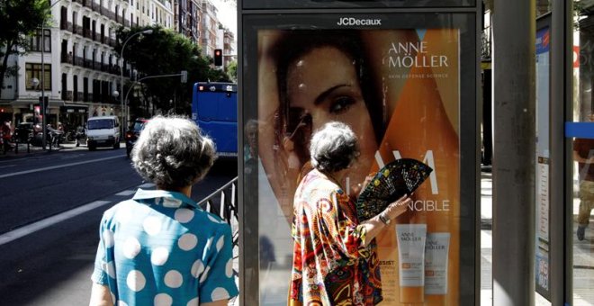 26/6/2019.- Dos mujeres que esperan la llegada del autobús observan los 35 grados que marca el termómetro de la marquesina a mediodía de hoy. La ola de calor, que comienza este miércoles, y que se prevé muy adversa por su intensidad, duración y extensión,