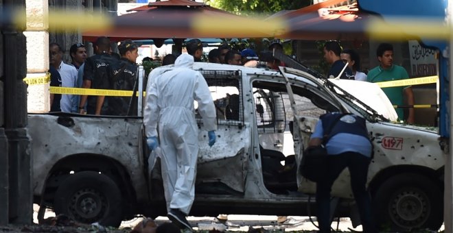 Dos investigadores analizan uno de los vehículos que ha hecho explosión este jueves en la capital de Túnez. /AFP