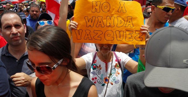 Una mujer sostiene una pancarta durante las protestas en San Juan / REUTERS