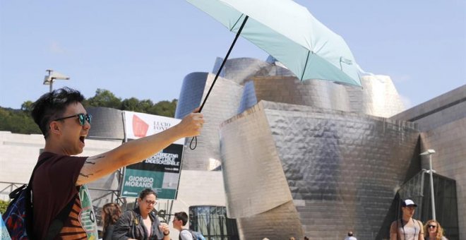 Un turista se protege del sol ante el museo Guggenheim de Bilbao, uno de los destinos demandados en vacaciones. /EFE