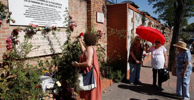 Una mujer coloca una rosa en el muro dedicado a las 13 jóvenes republicanas en el homenaje convocado por el PCE. / EFE