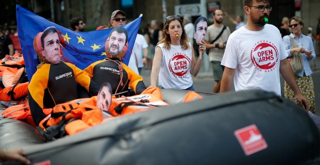 13/07/2019 - Manifestantes sostienen un bote hinchable con imágenes de las caras del presidente Pedro Sánchez y el ministro del Interior italiano, Matteo Salvini, en una protesta en Barcelona. / AFP - PAU BARRENA