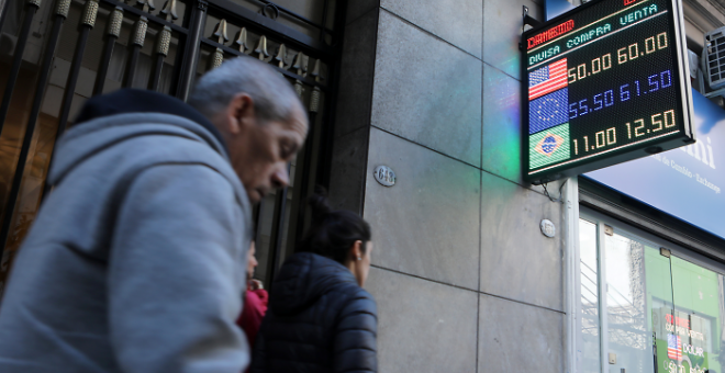 Los peatones pasan frente a un tablero electrónico que muestra los tipos de cambio en el distrito financiero de Buenos Aires | Reuters