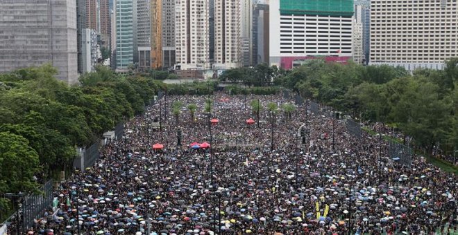 Una multitud se refugia de la lluvia bajo paraguas durante una nueva marcha contra el gobierno en Hong Kong. - EFE