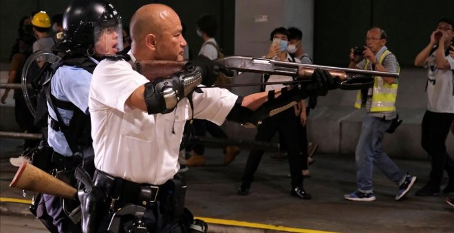 Un oficial de policía de Hong Kong apunta con un arma a los manifestantes. / TYRONE SIU (REUTERS)