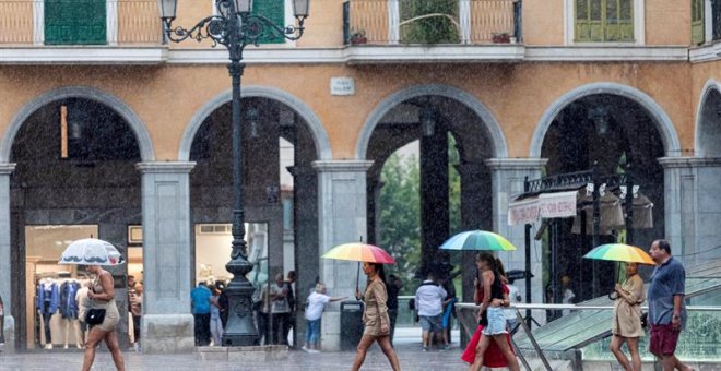 Varias personas se protegen con paraguas de la lluvia en la Plaza Mayor de Palma de Mallorca. /EFE