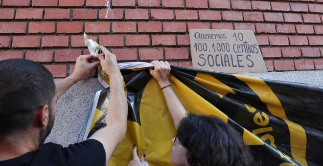 Dos jóvenes cuelgan una pancarta en la puerta de La Ingobernable.- EUROPA PRESS