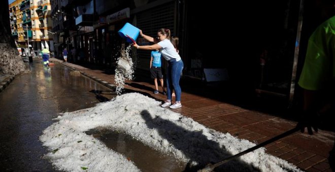 hoy27/08/2019.- Una ciudadana vacía un cubo de granizo en la calle después de la tormenta y la granizada que cayó este lunes en Arganda del Rey (Madrid) causando importantes daños materiales. EFE/ David Fernández