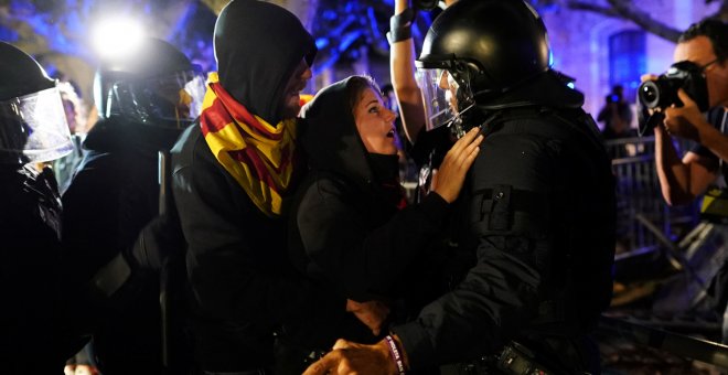 Una manifestante media ante un agente durante las protestas junto al Parlament. - REUTERS
