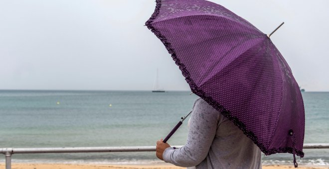Una mujer se protege de la lluvia este viernes en Palma de Mallorca. EFE/Cati Cladera