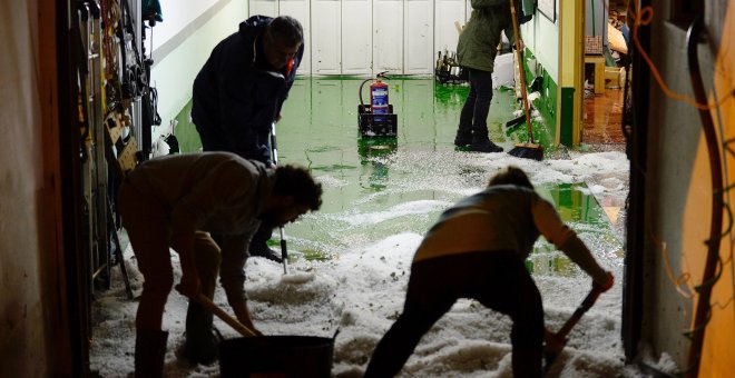 Un grupo de personas limpian el garaje de una vivienda en Viana de Cega, repleto de granizo. EFE/NACHO GALLEGO