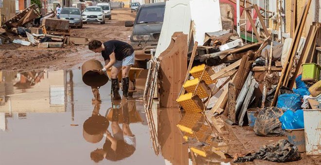 Una mujer vierte lodo en Cartagena, afectada por las inundaciones provocadas por las lluvias caídas en Murcia. / EFE