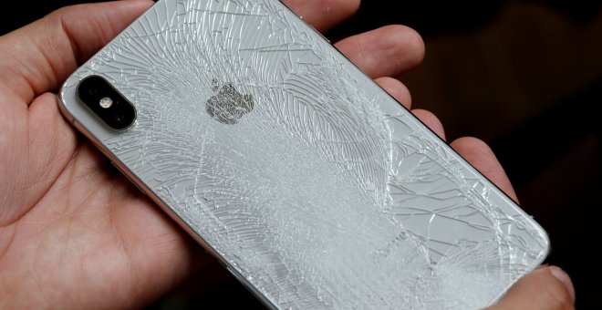 Un hombre sujeta un Smartphone de Apple, cuya carcasa posterior está agrietada./ REUTERS