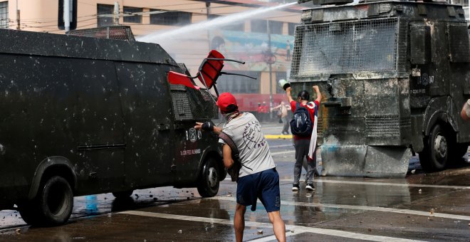 Manifestantes lanzan sillas a las furgonetas policiales en Santiago de Chile. /REUTERS