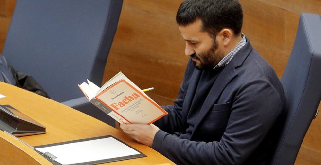 El conseller de Educación y Deportes de la Generalitat, Vicent Marzá, lee el libro 'Facha' durante la intervención del diputado de Vox, Jose María Llanos, en el debate en Les Corts Valencianes. (KAI FÖRSTERLING | EFE)