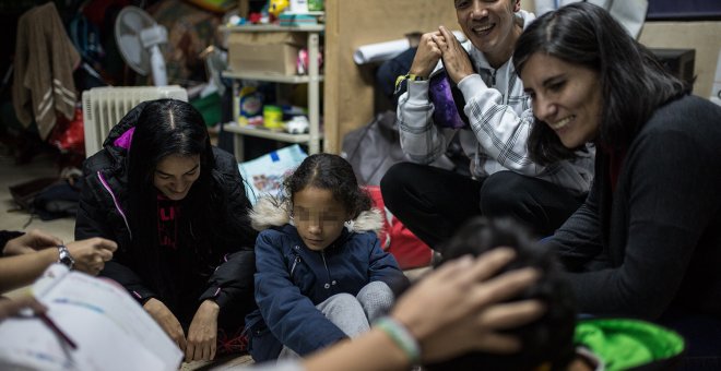 Julio Aponte junto a su mujer Margareth Jiménez (izquierda), juegan con sus hijos y la abogada Patricia Fernández en la habitación de la parroquia San Carlos Borromeo de Entrevías, donde llevan casi cinco meses esperando un plaza en el sistema de asilo y