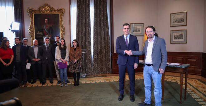 El presidente del Gobierno en funciones, Pedro Sánchez y el líder de Podemos, Pablo Iglesias, se estrechan la mano en el Congreso de los Diputados tras firmar el principio de acuerdo para compartir un gobierno de coalición tras las elecciones generales de