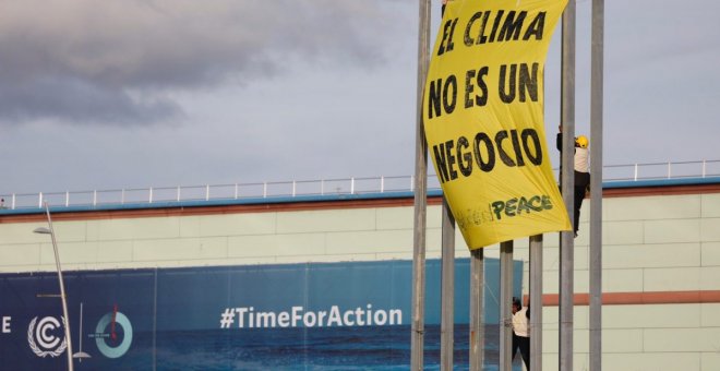 Varios activistas de Greenpeace despliegan una pancarta en una torre de iluminación del recinto ferial IFEMA, en la jornada final de la Cumbre del Clima COP25, este viernes, en Madrid. Los activistas protestan contra la "mercantilización de las negociacio