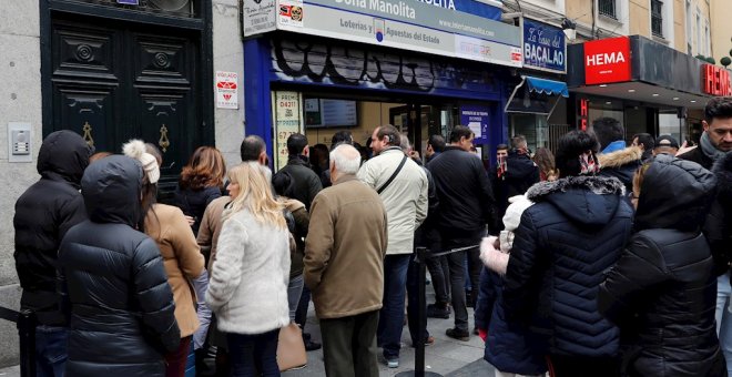 08/12/2019.- Decenas de personas hacen cola  en la administración de Loterías Doña Manolita, en Madrid, para comprar la tradicional lotería de Navidad. / EFE - BALLESTEROS
