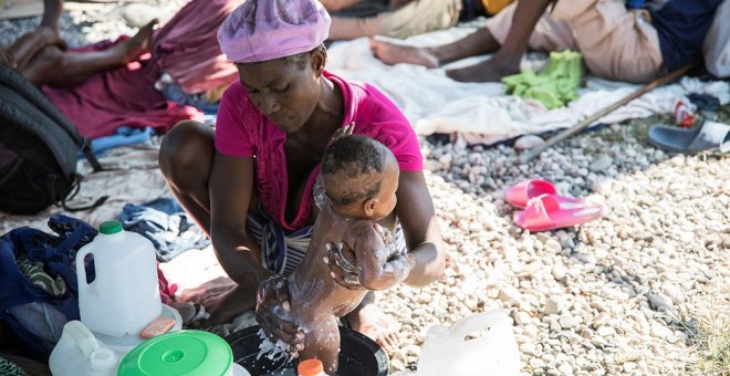 Una mujer baña a su bebé en un campamento en Puerto Príncipe, Haití. REUTERS