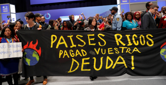Manifestantes con un cartel en el que se lee: "Países ricos pagad vuestra deuda!"./ Susana Vera (Reuters)