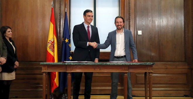 El candidato a la investidura, Pedro Sánchez (i), y el líder de Podemos, Pablo Iglesias (d), estrechan sus manos durante el acto de firma del acuerdo programático con las principales medidas que tomará el futuro Gobierno de coalición. EFE/JuanJo Martín