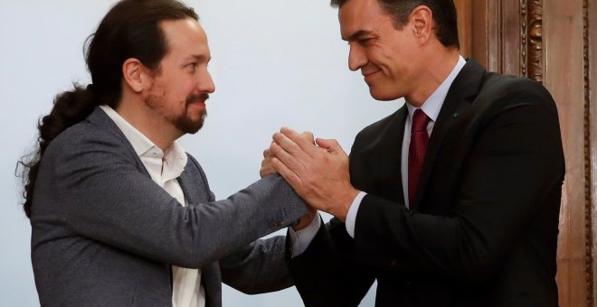 El candidato a la investidura, Pedro Sánchez (d), y el líder de Podemos, Pablo Iglesias (i), estrechan sus manos tras el acto de firma del acuerdo programático con las principales medidas que tomará el futuro Gobierno de coalición.EFE/JuanJo Martín