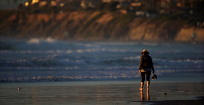 Una mujer pasea en una playa de Cardiff (California). REUTERS/Mike Blake