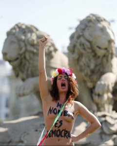 Una de las cuatro activistas de Femen que hoy se han encaramado en una acción sorpresa a la fuente de Cibeles para protestar contra la ley mordaza.- EFE/Juan Carlos Hidalgo