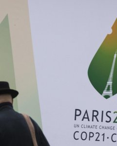 Un hombre pasa por delante del cartel de la cumbre del clima en París. REUTERS