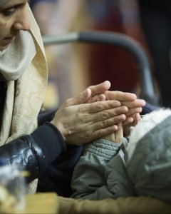 Una mujer calienta las manos de su hijo en una tienda de campaña.- EFE