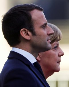 El Presidente francés Emmanuel Macron y la canciller alemana Angela Merkel escuchando los himnos nacionales durante un acto en la Cancillería de Berlín REUTERS/Fabrizio Bensch