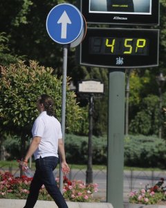 Un hombre camina con una botella de agua en la mano por una calle del centro de Córdoba, a su paso por un termómetro que indica 45 grados. EFE/Salas