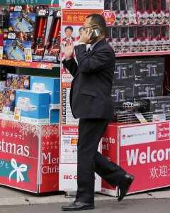 Un hombre habla por el móvil junto a una tienda de electrónica de Tokio.. REUTERS/Thomas Peter