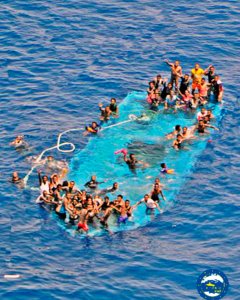 Un grupo de inmigrantes sobre la barcaza parcialmente sumergida que fueron rescatados por la fragata española 'Reina Sofia' la semana pasada. REUTERS