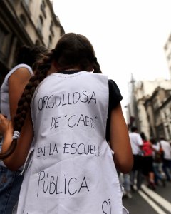Una niña porta un cartel en la espalda que reza 'Estoy orgulloso de caer en la escuela pública' sobre su uniforme escolar después de la gafe de ayer del presidente argentino Mauricio Macri sobre los argentinos que 'caen en la escuela pública' durante una