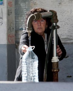 Una vecina de Vigo se abastece de agua potable en una fuente pública. / EFE