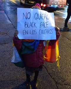 Una niña racializada porta un mensaje en contra del 'Black Face' después de que a ella y todos sus compañeros del colegio les pintaran la cara de negro para simbolizar que eran africanos, según ha denunciado su madre. | Guillermo Martínez