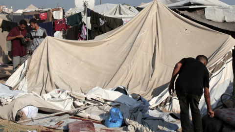 Palestinos miran el daño causado por un ataque israelí en Jan Yunis. Palestinos miran el daño causado por un ataque israelí en Jan Yunis.