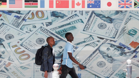 Un par de personas pasa  junto a una imagen de billetes de dólares, en el exterior de una casa de cambio en el centro de Nairobi (Kenia).