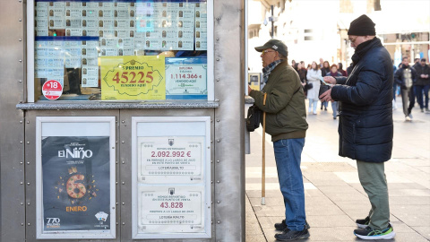 Varias personas hacen cola en un quiosco para comprar décimos.